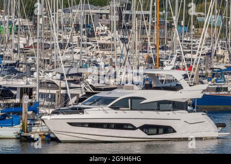 Yachten und Motorboote neben dem Yachthafen im Hafen für Kreuzfahrten von Seglern und Motorbooten in lymington, New Forest hampshire. Stockfoto