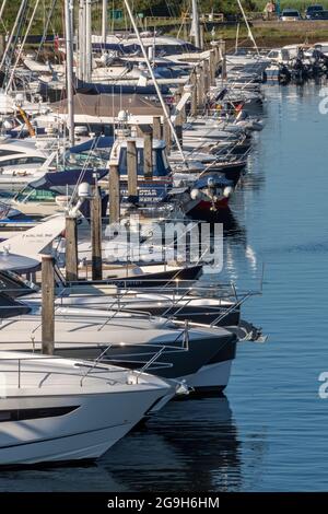 Yachten und Motorboote neben dem Yachthafen im Hafen für Kreuzfahrten von Seglern und Motorbooten in lymington, New Forest hampshire. Stockfoto