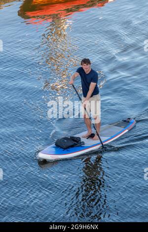 Ein Mann auf einem Stand-up-Paddle-Board auf dem Meer paddelt in Shorts und hält das Gleichgewicht.