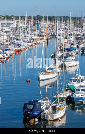 Yachten und Motorboote neben dem Yachthafen im Hafen für Kreuzfahrten von Seglern und Motorbooten in lymington, New Forest hampshire. Stockfoto