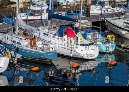 Yachten und Motorboote neben dem Yachthafen im Hafen für Kreuzfahrten von Seglern und Motorbooten in lymington, New Forest hampshire. Stockfoto