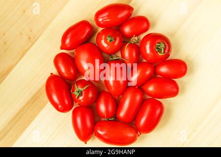 Rote Kirschtomaten Pflaumenform reif auf Holztisch Hintergrund. Saisonale Markt lokale Produkte. Stockfoto