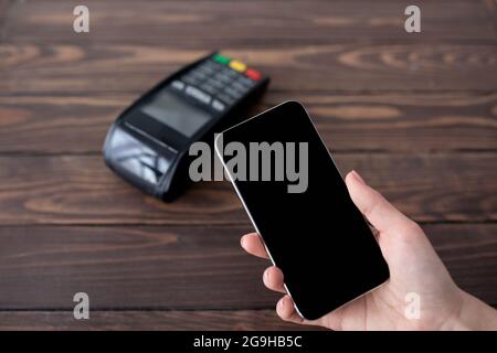 Lady zahlt kontaktlos vom Smartphone mit moderner easy nfc-Technologie, hält Handy mit leerem Bildschirm, Nahaufnahme. Kartenlesegerät, das die Bezahlung macht Stockfoto