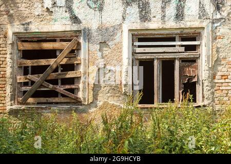 Zwei Fenster eines alten verlassenen Hauses auf der Straße der Stadt am Sommertag Stockfoto
