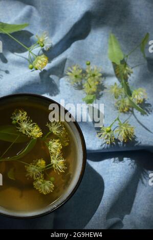 Tasse mit Lindentee und Blumen und natürlichem Licht Stockfoto