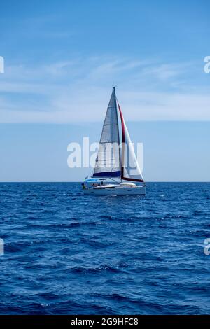 Segeln in der Ägäis Griechenland. Segelboot mit offenen weißen Segeln, ruhigem, gewellten Meer, blauer Himmel im Hintergrund, sonniger Tag. Ferien Cyclades i im Sommer Stockfoto