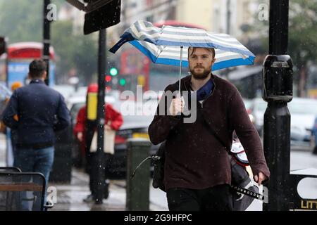 London, Großbritannien. Juli 2021. Ein Mann schützt sich nach der jüngsten Hitzewelle unter einem Regenschirm in London vor Regen. Kredit: SOPA Images Limited/Alamy Live Nachrichten Stockfoto