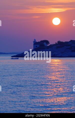 Schöner Sonnenuntergang über dem verlassenen Leuchtturm auf der kroatischen Insel Murter in der Adria und Fischer in einem Boot. Urlaub, Reisen, Tourismus, Sommer und Erbse Stockfoto