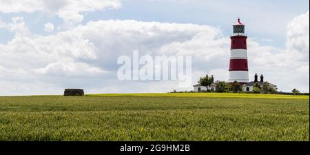 Der farbenfrohe Leuchtturm von Happisburgh, der in der Nähe einer alten „Pillenbox“ der Verteidigung steht, wurde am 5. Juli 2021 aufgenommen. Stockfoto