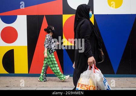 London, Großbritannien. 26. Juli 2021. Die Käufer kommen an einem bunten Horten vorbei, das die Außenfassade einer Zweigstelle eines geschlossenen Topshop-Stores in der Oxford Street bedeckt. Ein aktueller Bericht von Barclays hat gezeigt, dass die hohen Straßenausgaben nicht signifikant gestiegen sind, obwohl die Beschränkungen für die Sperrung durch die Coronavirus-Pandemie gelockert wurden, da die Käufer weiterhin online einkaufen. Kredit: Stephen Chung / Alamy Live Nachrichten Stockfoto