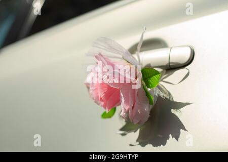 Blütenknospe an der Autotür. Hochzeitsdekoration am Türgriff des Autos. Eine symbolische Blume im Transport. Stockfoto