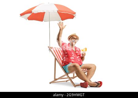 Reifer männlicher Tourist, der mit einem Cocktail unter einem Regenschirm sitzt und isoliert auf weißem Hintergrund winkt Stockfoto