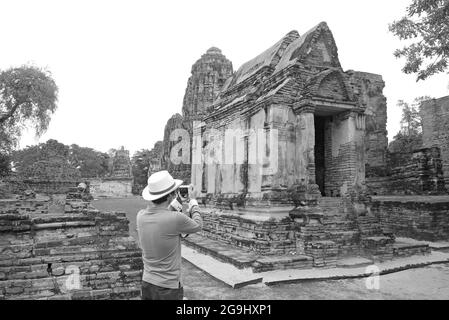 Monochromes Bild eines Besuchers, der die Überreste des Wat Mahathat Tempels im Ayutthaya Historical Park, Thailand, fotografiert Stockfoto