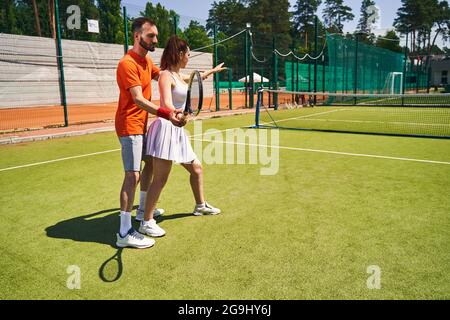 Ein erfahrener Trainer lehrt einen Anfänger, den Schläger zu halten Stockfoto