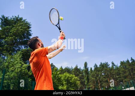 Kaukasischer Sportler, der einen Overhead-Tennis-Dienst durchführt Stockfoto