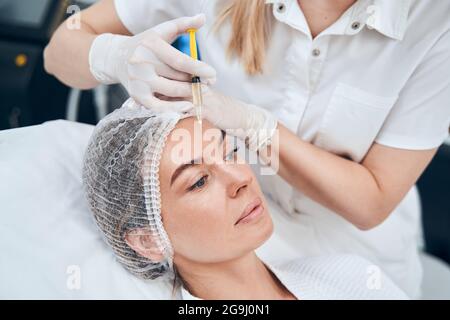 Freundliche weibliche Person, die Injektion in die Stirn macht Stockfoto