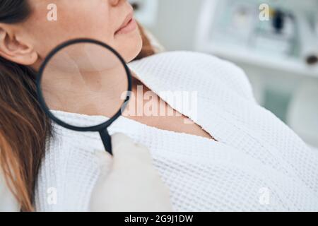 Professioneller Kosmetologe, der die weibliche Haut untersucht Stockfoto