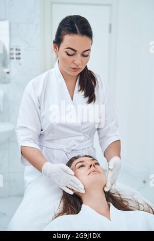 Kompetenter Arzt, der die Gesichtsmassage korrigiert Stockfoto