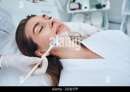 Sachkundiger Meister, der für das Verfahren eine Bürste verwendet Stockfoto