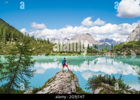 Rucksacktourist mit Rucksack, der die türkisfarbene Aussicht auf den Lago di Sorapiss auf 1.925m Höhe (Bergsee) genießt, da er Bergwanderung in den Dolomiten hat, I Stockfoto