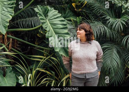 Frau mit Händen in Gesäßtaschen mit Laub Hintergrund kopieren Raum Stockfoto