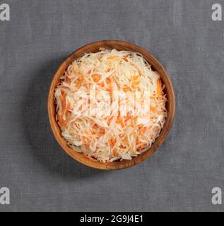 Sauerkraut in einer Holzschale auf grauem Hintergrund Nahaufnahme. Fermentierte Lebensmittel. Kohlsalat mit Karotten. Draufsicht, flach liegend. Stockfoto