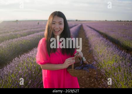 Junge asiatische Frau im Freien auf Lavendel Blumen Feld - glücklich und schön chinesisches Mädchen in süßen Sommer magenta Kleid genießen Urlaub entspannt auf pur Stockfoto