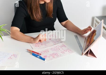 Illustrator Woman zeichnet Skizzen, die auf ihrem Schreibtisch sitzen Stockfoto