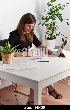 Illustrator Woman zeichnet Skizzen, die auf ihrem Schreibtisch sitzen Stockfoto