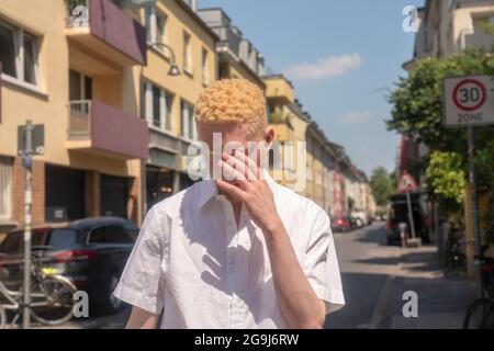 Deutschland, Köln, Albino Mann in weißem Hemd auf der Straße Stockfoto