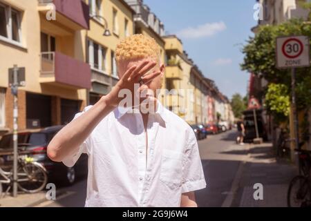 Deutschland, Köln, Albino Mann in weißem Hemd auf der Straße Stockfoto