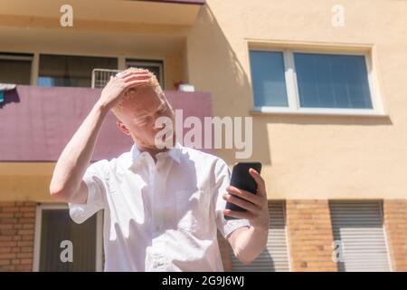 Deutschland, Köln, Albino Mann in weißem Hemd mit Smartphone Stockfoto