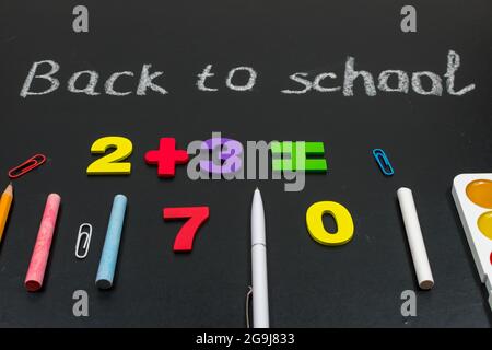 Bunte Zahlen, Zählstöcke, mathematische Zeichen auf einer Tafel. Zurück zur Schule. Konzepte. Schulbedarf auf einer Tafel. Blick von oben Stockfoto