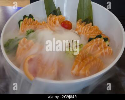 Nahaufnahme einer Schüssel mit einem geräucherten, köstlichen Lachs, der mit frischem Gemüse dekoriert ist Stockfoto