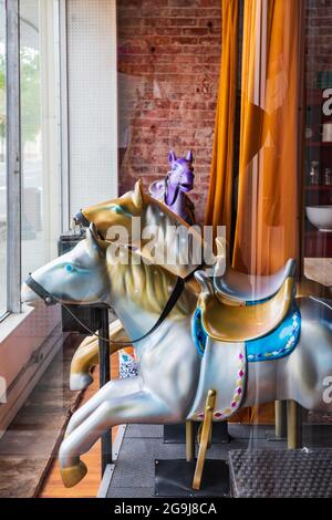 Colfax, Washington, USA. 22.Mai 2021. Karussellpferde im Fenster eines kleinen Stadtladens. Stockfoto