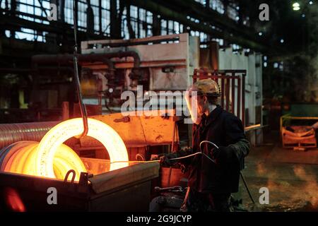 Arbeiter in Schutzkleidung schmelzen Metall während seiner Arbeit in Die Fabrik Stockfoto