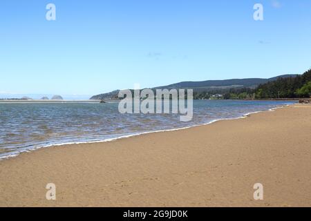 Entlang der Küste von Oregon: Netarts Bay und Shellfish Preserve bei Ebbe sind die Three Arch Rocks direkt vor der Küste am Horizont zu sehen. Stockfoto