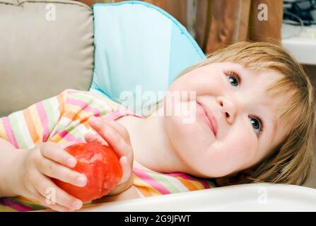 Kleines Mädchen hält eine Tomate und lächelt Stockfoto