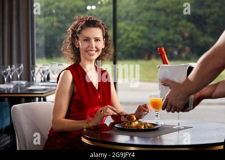 Der Kellner brachte Champagner und Eiskübel mit der jungen Frau im Restaurant Stockfoto