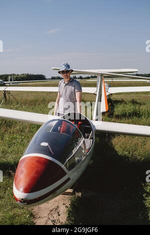 Der Segelflieger bereitet sich auf den Flug mit motorlosen Festflügelflugzeugen vor. Kleine Luftfahrt Extremsport Freizeitbeschäftigung. Mann in der Nähe des Flugzeugs Stockfoto