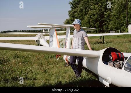 Der Segelflieger bereitet sich auf den Flug mit motorlosen Festflügelflugzeugen vor. Kleine Luftfahrt Extremsport Freizeitbeschäftigung. Mann in der Nähe des Flugzeugs Stockfoto