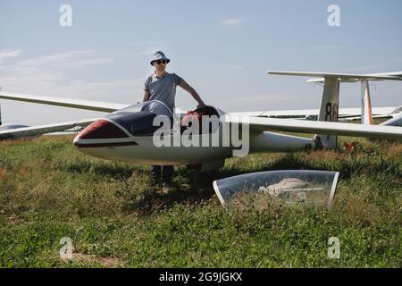 Der Segelflieger bereitet sich auf den Flug mit motorlosen Festflügelflugzeugen vor. Kleine Luftfahrt Extremsport Freizeitbeschäftigung. Mann in der Nähe des Flugzeugs Stockfoto