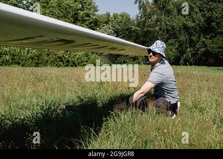 Der Segelflieger bereitet sich auf den Flug mit motorlosen Festflügelflugzeugen vor. Kleine Luftfahrt Extremsport Freizeitbeschäftigung. Mann in der Nähe des Flugzeugs Stockfoto