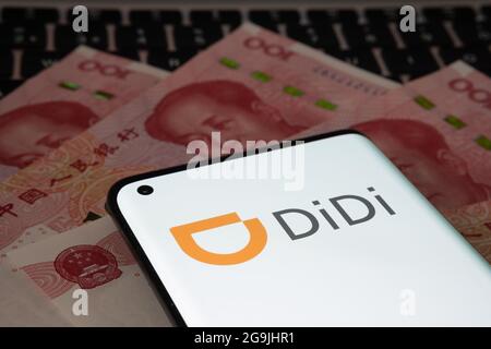 Didi Chuxing Technology Firmenlogo auf dem Smartphone auf 100 Yuan-Banknoten platziert gesehen. Konzept. Stafford, Großbritannien, 26. Juli 2021. Stockfoto