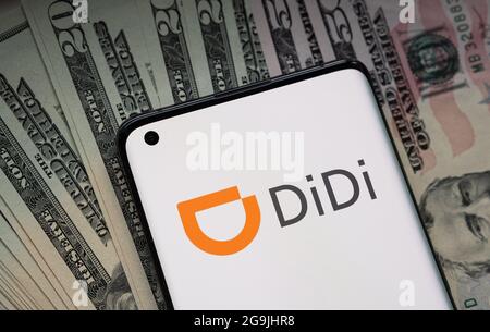 Didi Chuxing Technology Firmenlogo auf dem Smartphone auf Stapel von US-Dollar platziert gesehen. Konzept. Stafford, Großbritannien, 26. Juli 2021. Stockfoto