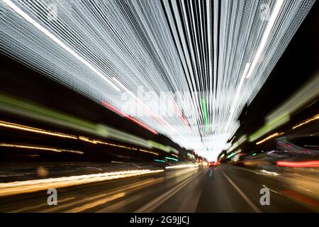 Fahren In Der Stadt. Leichter Regen. Langzeitbelichtung. Blick durch die Windschutzscheibe während der Nachtfahrt. Langzeitbelichtung. Künstlerisch, abstrakt. Stockfoto