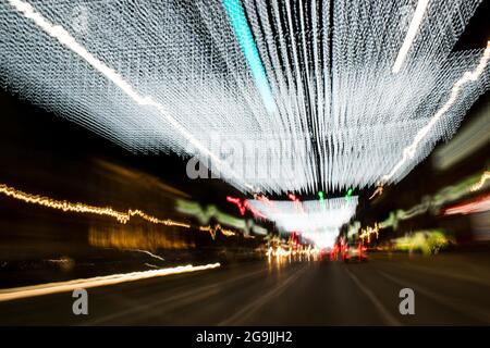 Fahren In Der Stadt. Leichter Regen. Langzeitbelichtung. Blick durch die Windschutzscheibe während der Nachtfahrt. Langzeitbelichtung. Künstlerisch, abstrakt. Stockfoto