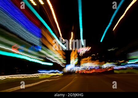 Fahren In Der Stadt. Leichter Regen. Langzeitbelichtung. Blick durch die Windschutzscheibe während der Nachtfahrt. Langzeitbelichtung. Künstlerisch, abstrakt. Stockfoto