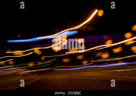 Fahren In Der Stadt. Leichter Regen. Langzeitbelichtung. Blick durch die Windschutzscheibe während der Nachtfahrt. Langzeitbelichtung. Künstlerisch, abstrakt. Stockfoto