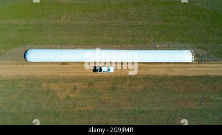 Luftaufnahme des 4x4 Pickup-LKW, der durch Weizenanbau-Feld mit Silosäcken auf der Straße fährt. Argentinien Stockfoto